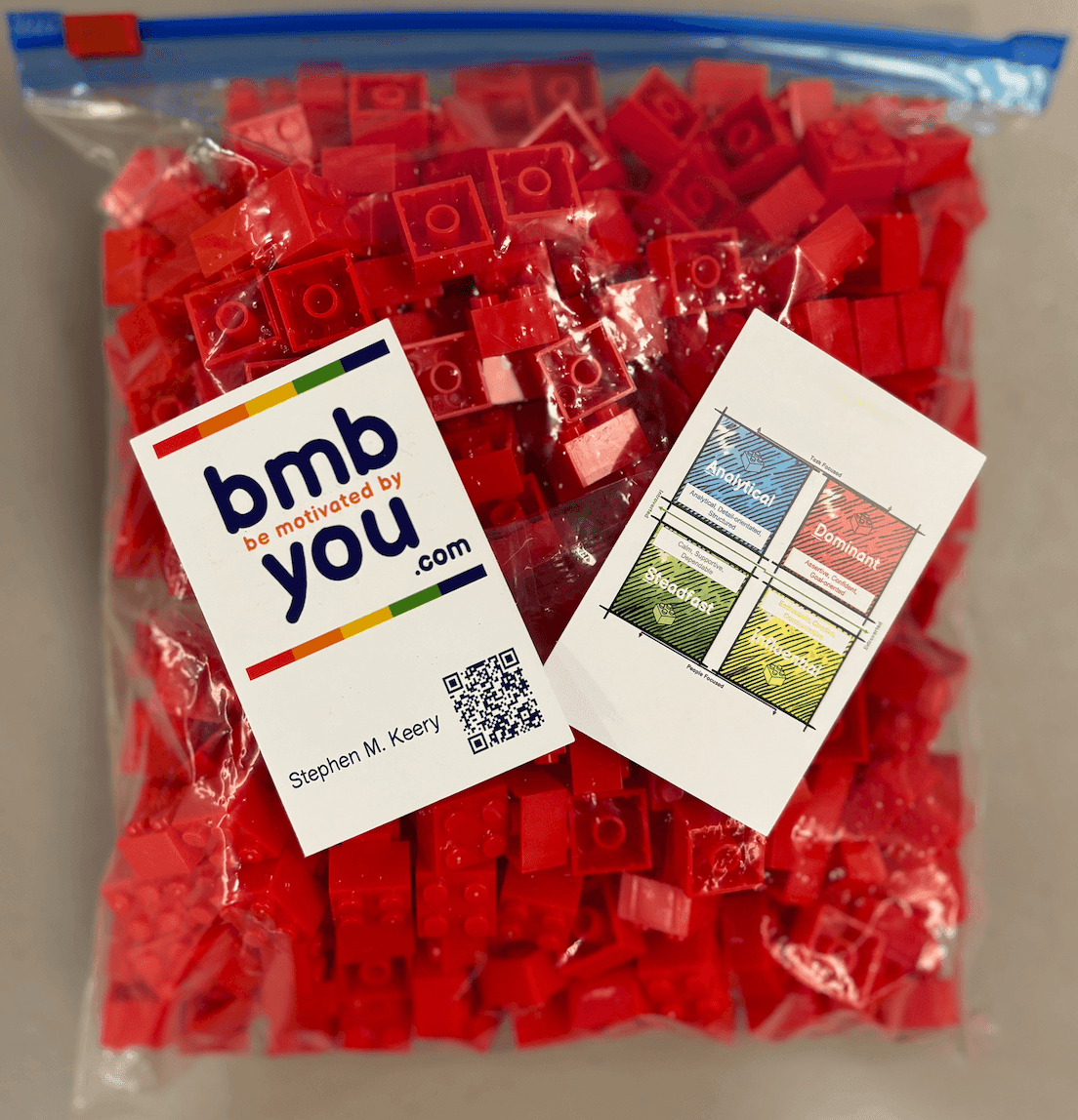 Bag of red plastic building blocks with motivational cards and QR code.